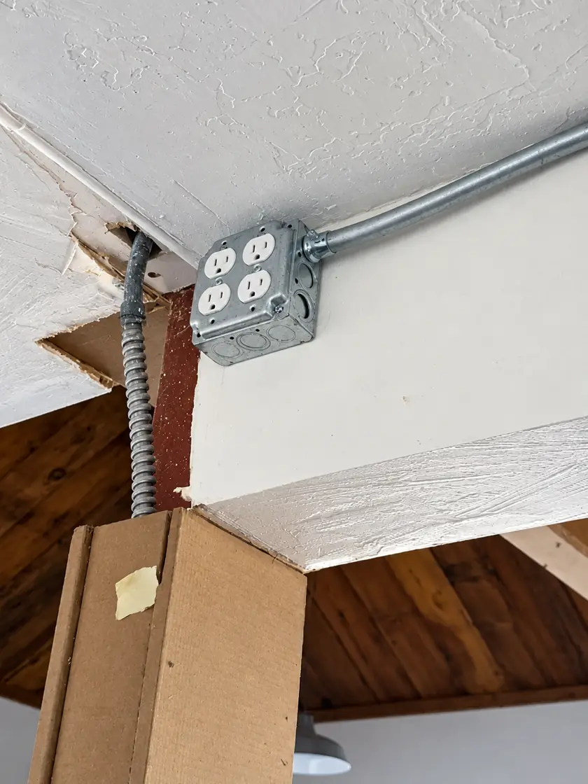 Surface outlet box with flexible conduit mounted to a ceiling