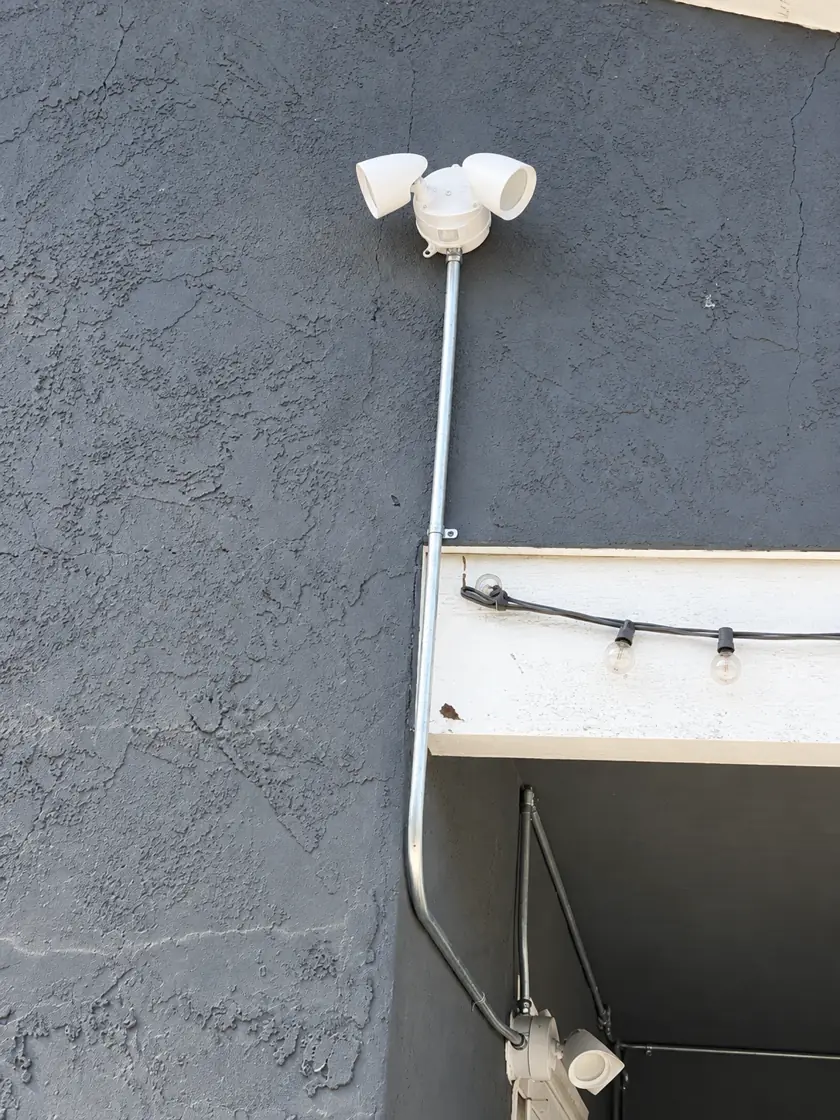 Exterior flood lights and conduit on a commercial stucco wall
