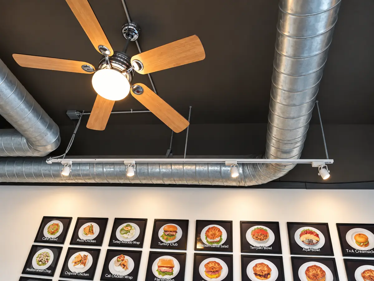 Ceiling fan and track lighting in a restaurant with exposed ductwork