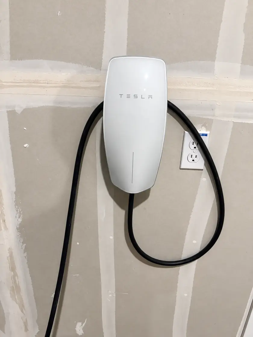 Tesla Wall Connector mounted in a garage with a dedicated 240V outlet